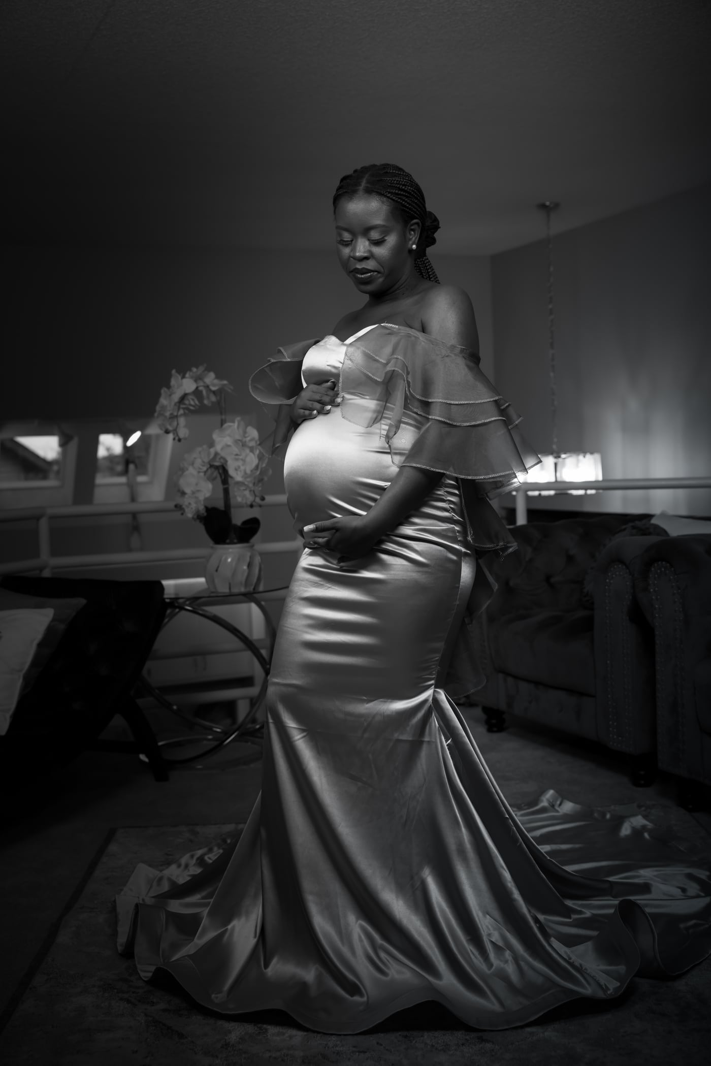 Satin gown, B&W window light, elegant silhouette, editorial maternity. Photograph by Samuel Mfinanga for Mfinanga Photography + Motion.